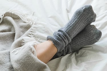 Die Füße einer Frau sind in dicke graue Wollsocken eingepackt